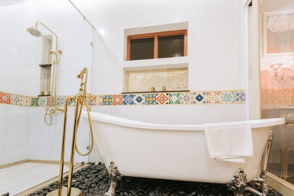 A bathroom with a freestanding bathtub, a shower with a gold showerhead, and a window with a wooden frame. - Chuchai Buri Sri Amphawa (Amphawa)