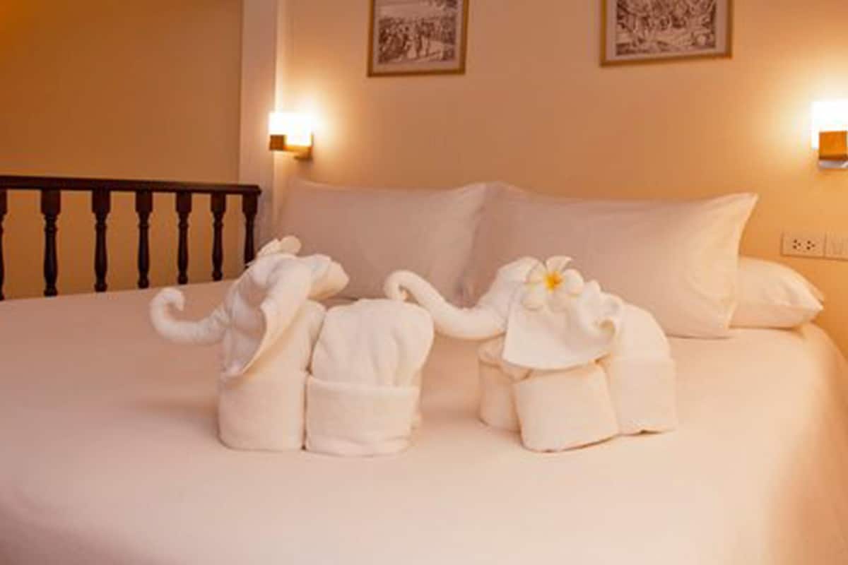 A bed with two elephant-shaped bathrobes and a pillow.