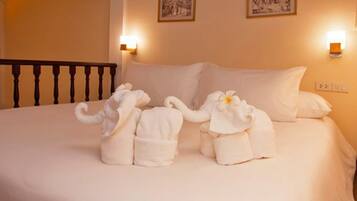 Una cama con dos albornoces con forma de elefante y una almohada.