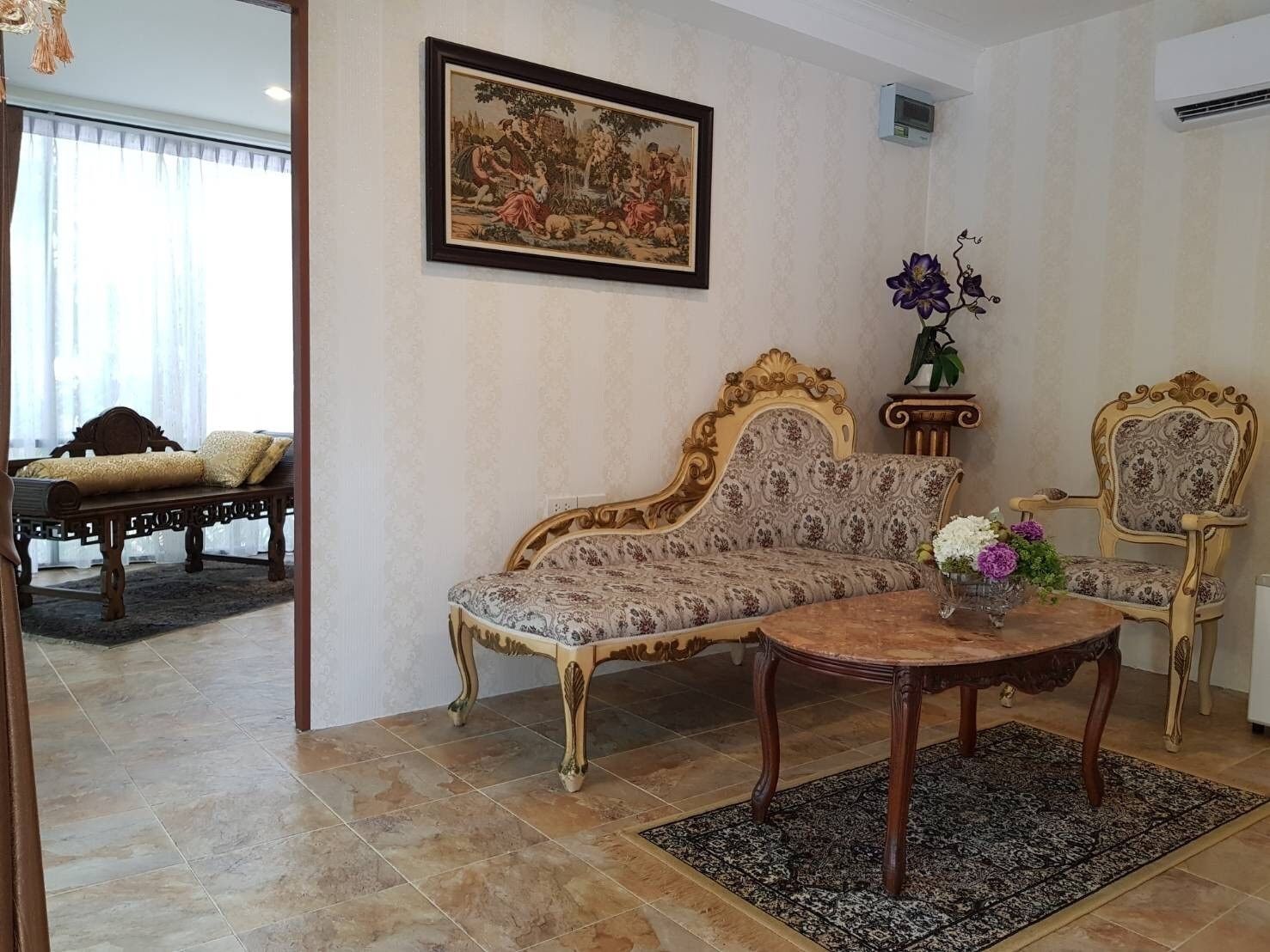 A living room with a sofa, a chair, a coffee table, and a painting on the wall.
