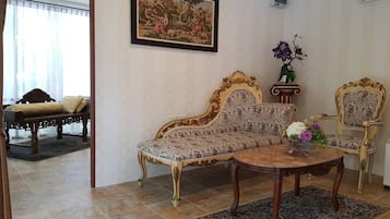 A living room with a sofa, a chair, a coffee table, and a painting on the wall.