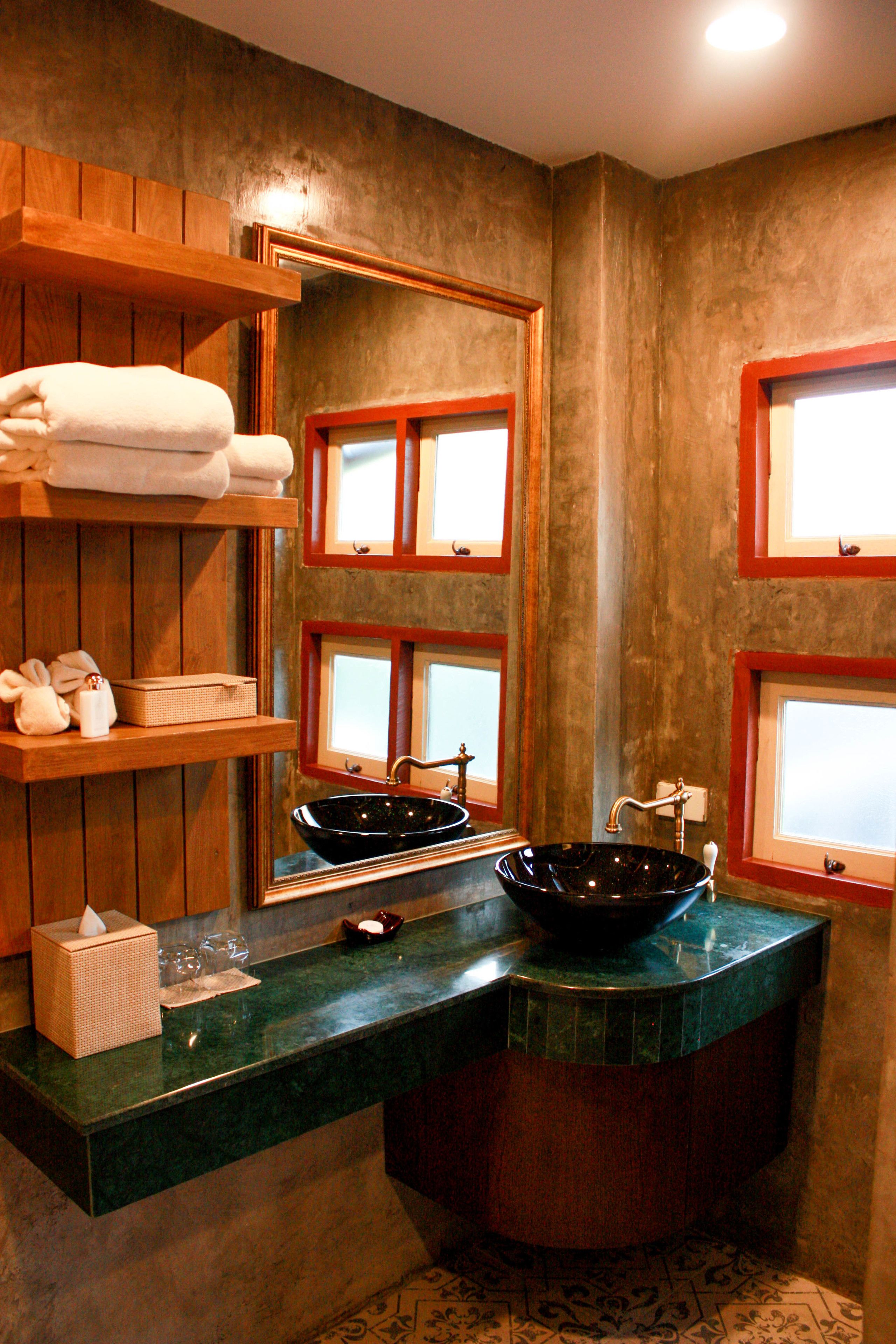 A bathroom with a large mirror, wooden shelves with towels, a black sink, and a green countertop.