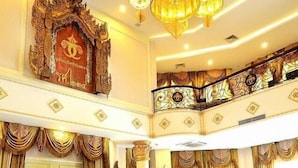 Un amplio vestíbulo con una zona de estar circular, candelabros ornamentales y un balcón con barandillas intrincadas.