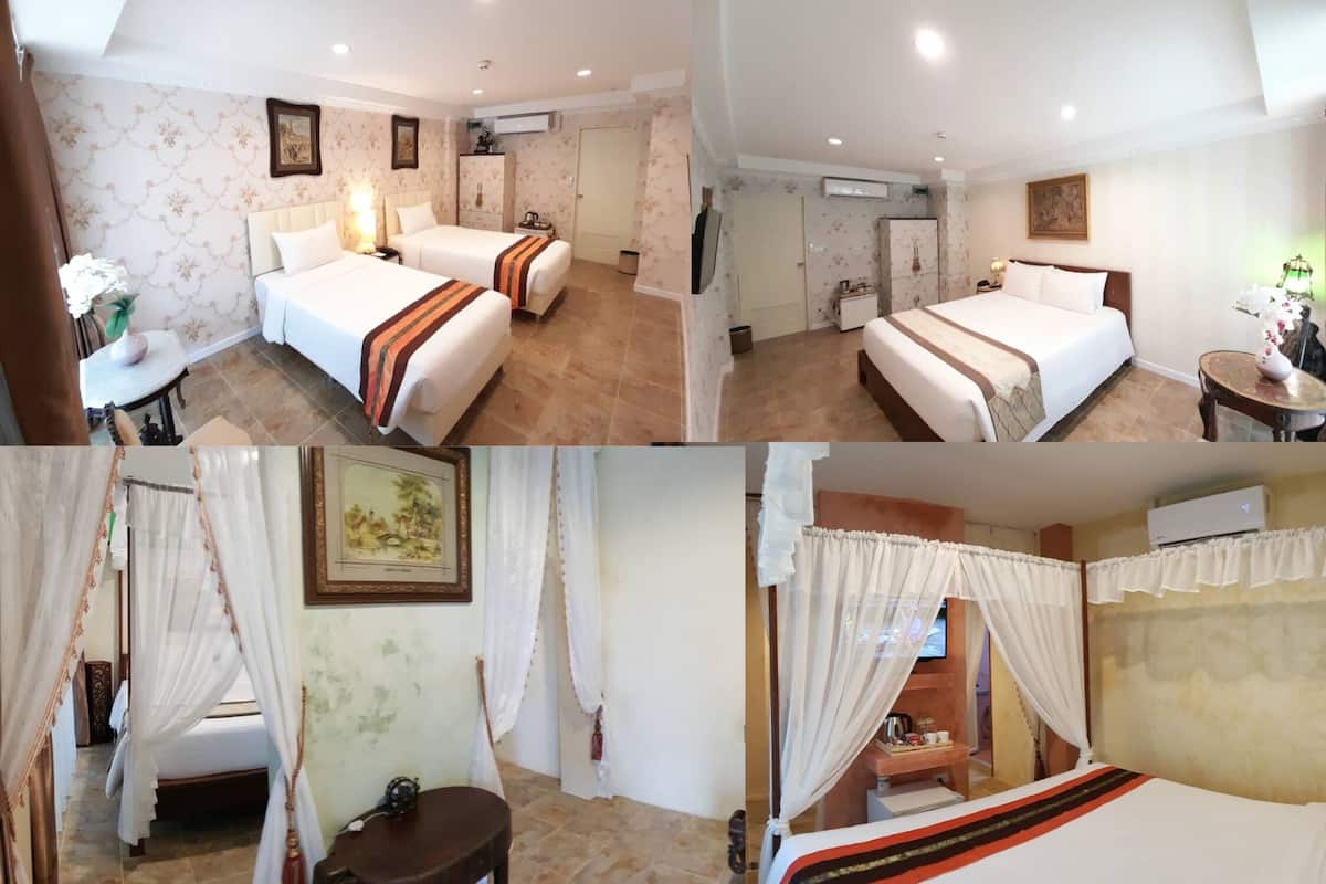 A hotel room with two beds, a small table, a chair, an air conditioning unit, and a television.