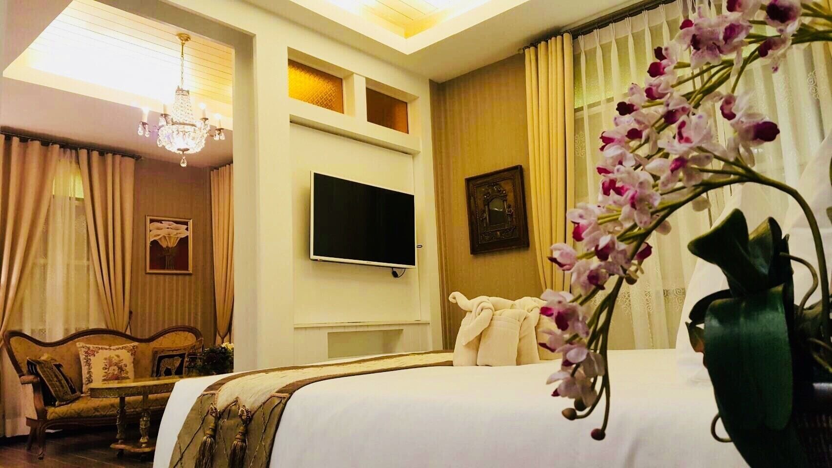 Ein Hotelzimmer mit Bett, Fernseher, Sofa und einer Kristallleuchtre.