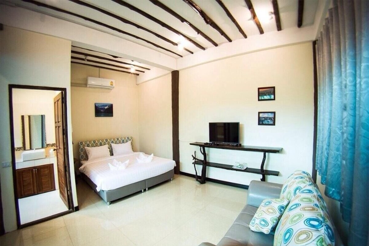 A hotel room with a bed, a TV, a sofa, and a desk.