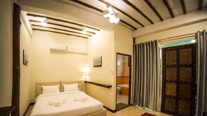 A hotel room with a bed, a bedside table, a mirror, a shower area, and a wooden floor. - Rao Ga Khao Resort (Pak Chong)