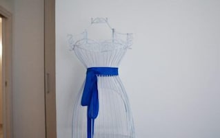 Un mannequin portant une robe blanche avec une ceinture bleue.