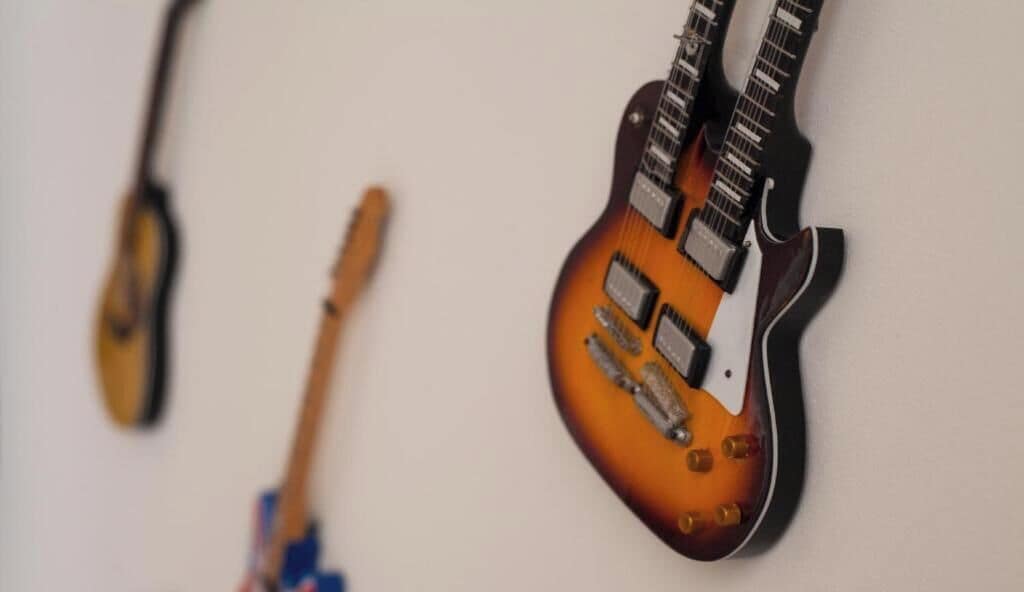 A wall with two guitars leaning against it.