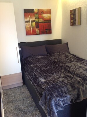 A bedroom with a bed, a headboard, a wall with abstract art, and a door. - Quiet apartment with terrace and water views (Garz/Rügen)