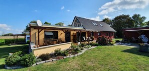 A two-story house with a patio, a satellite dish, and a garden. - Quiet apartment with terrace and water views (Garz/Rügen)