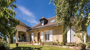 A two-story house with a stone facade, large windows, and a well-maintained lawn. - Villa with Pool in Corrèze (Saint Bonnet La Rivière)