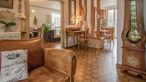 A cozy living room with a brown leather sofa, a wooden dining table, and a large grandfather clock. - Villa with Pool in Corrèze (Saint Bonnet La Rivière)