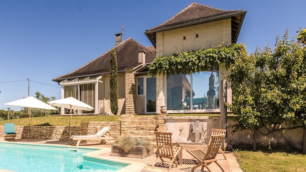 A house with a swimming pool, outdoor furniture, and a stone wall. - Villa with Pool in Corrèze (Saint Bonnet La Rivière)