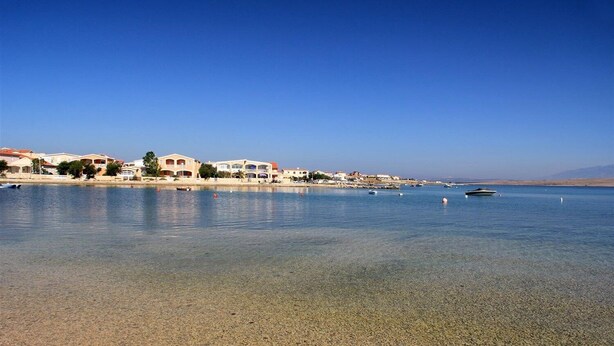 A coastal area with clear water, boats, and buildings along the shore.