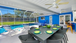 Patio esterno con piscina, tavolo da pranzo per quattro e ventilatore a soffitto.