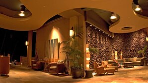 A warmly lit lobby with a stone wall, seating area, and a large potted plant.