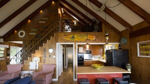 A spacious kitchen with a wooden island, bar stools, and a high ceiling with exposed beams. - Door County's Chalet On The Shore (Sturgeon Bay)