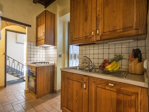 A kitchen with wooden cabinets, a gas stove, and a sink.