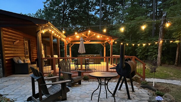 A wooden deck with outdoor furniture, a grill, and string lights.