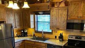 A kitchen with wooden cabinets, a stainless steel refrigerator, a coffee maker, a sink, and a stove.
