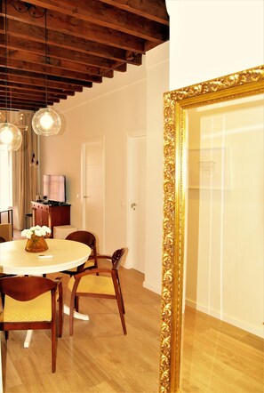 Un comedor con una mesa redonda, sillas y un espejo grande y ornamentado.