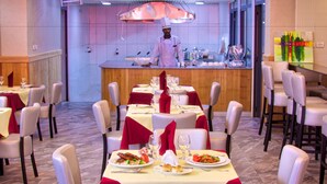 Een restaurant met gedekte tafels, een kok achter de bar, en een modern interieur.