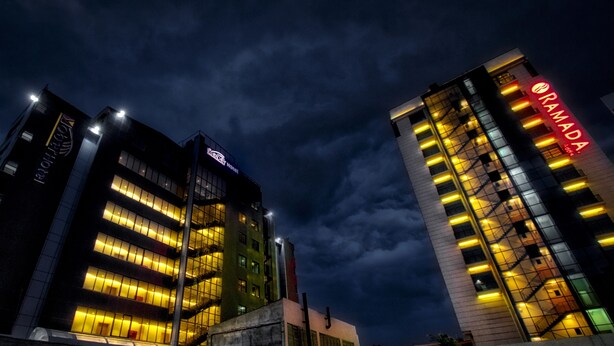 Een hotel met meerdere verdiepingen, verlichte ramen en een opvallend rood bord.