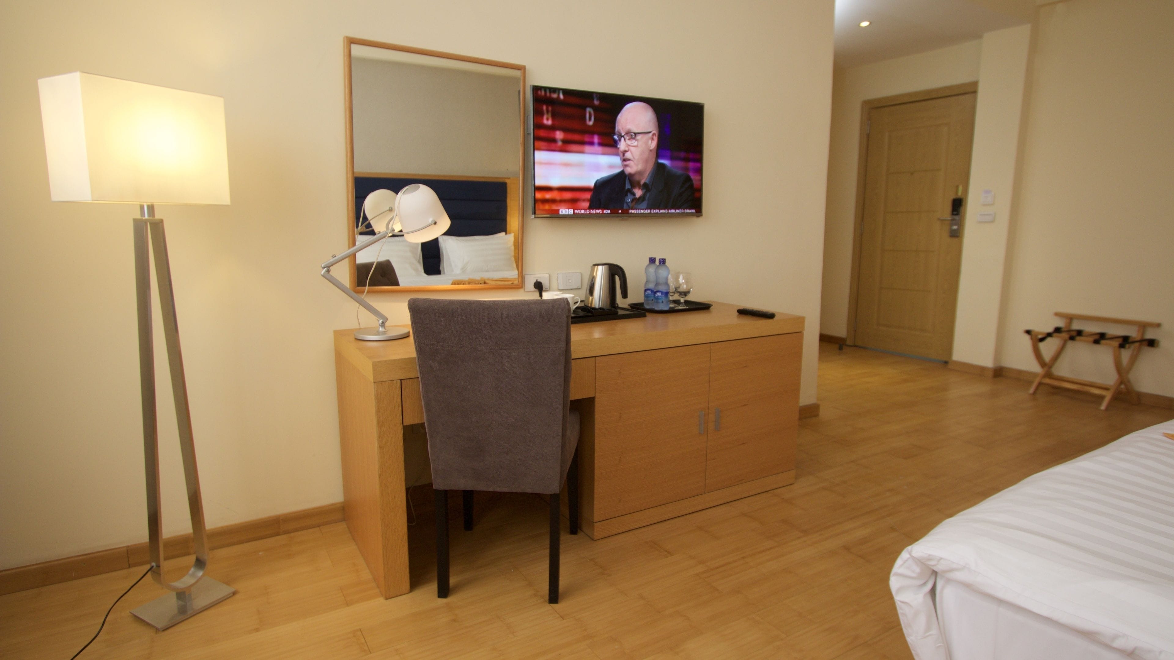 Una habitación de hotel con escritorio, silla, lámpara, televisión y cama.