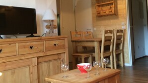 Ein Holzinterieur mit einem Fernseher, einem Tisch mit Weingläsern und einer roten Schüssel.