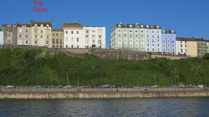 A waterfront view of colorful buildings with a stone wall in the foreground. - Sea View Apartment Tenby, Pembrokeshire, Wales. Near Beach, Restaurants & Shops (Tenby)