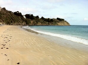 A sandy beach with footprints leading to the water, a calm sea, and a cliff with vegetation. - Pretty longère with enclosed garden, 3 *.  Ajoncs d'Or beaches and golf nearby. (Plourhan)