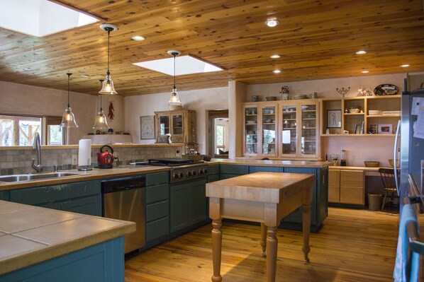 A spacious kitchen with wooden ceiling beams, a central island, and built-in cabinetry.
