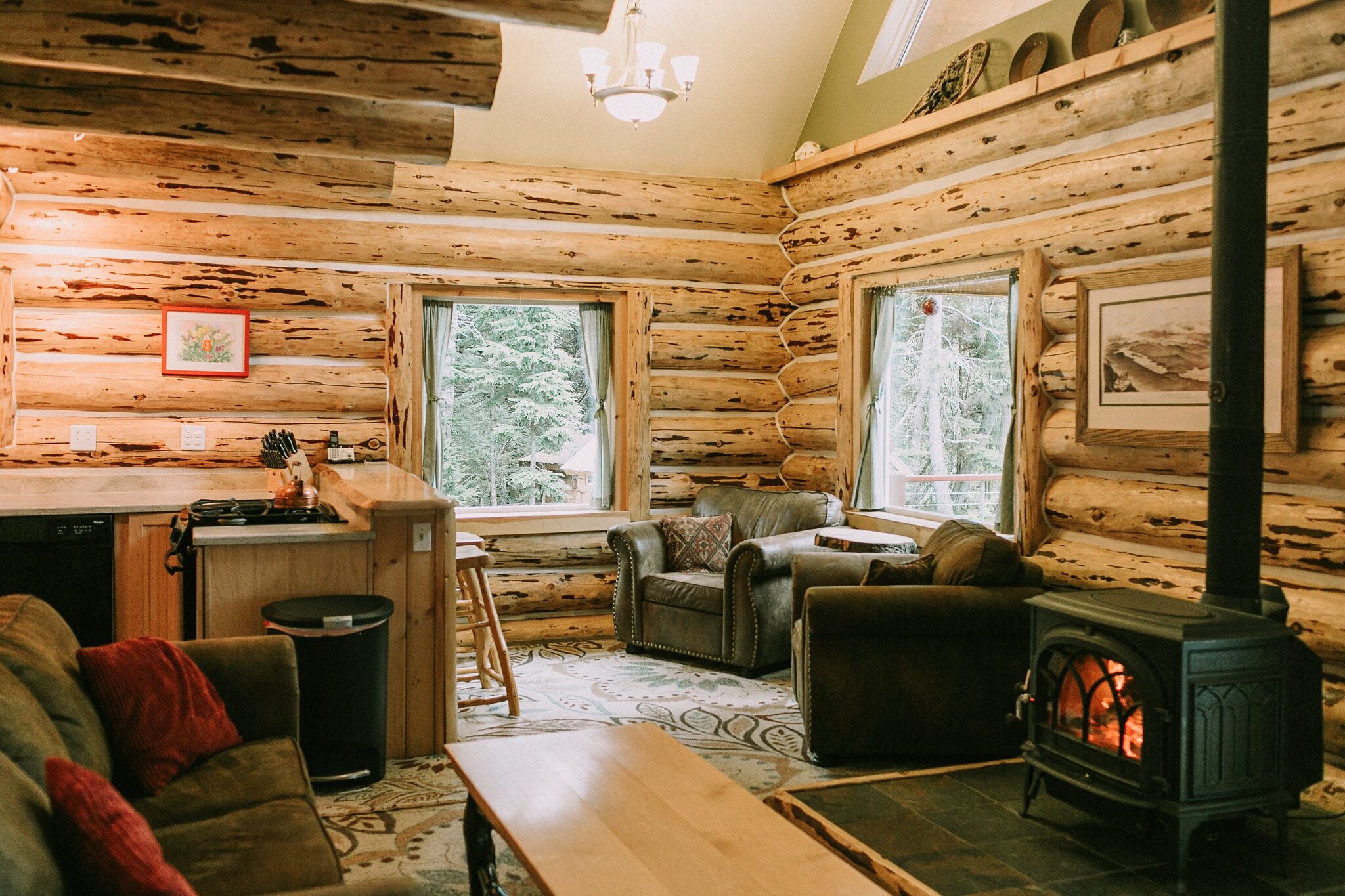 A log cabin interior with a kitchen, dining area, and a fireplace.