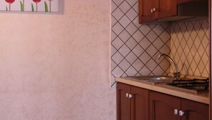 Una cocina con armarios de madera, salpicadero de azulejos y un cuadro de tulipanes rojos.