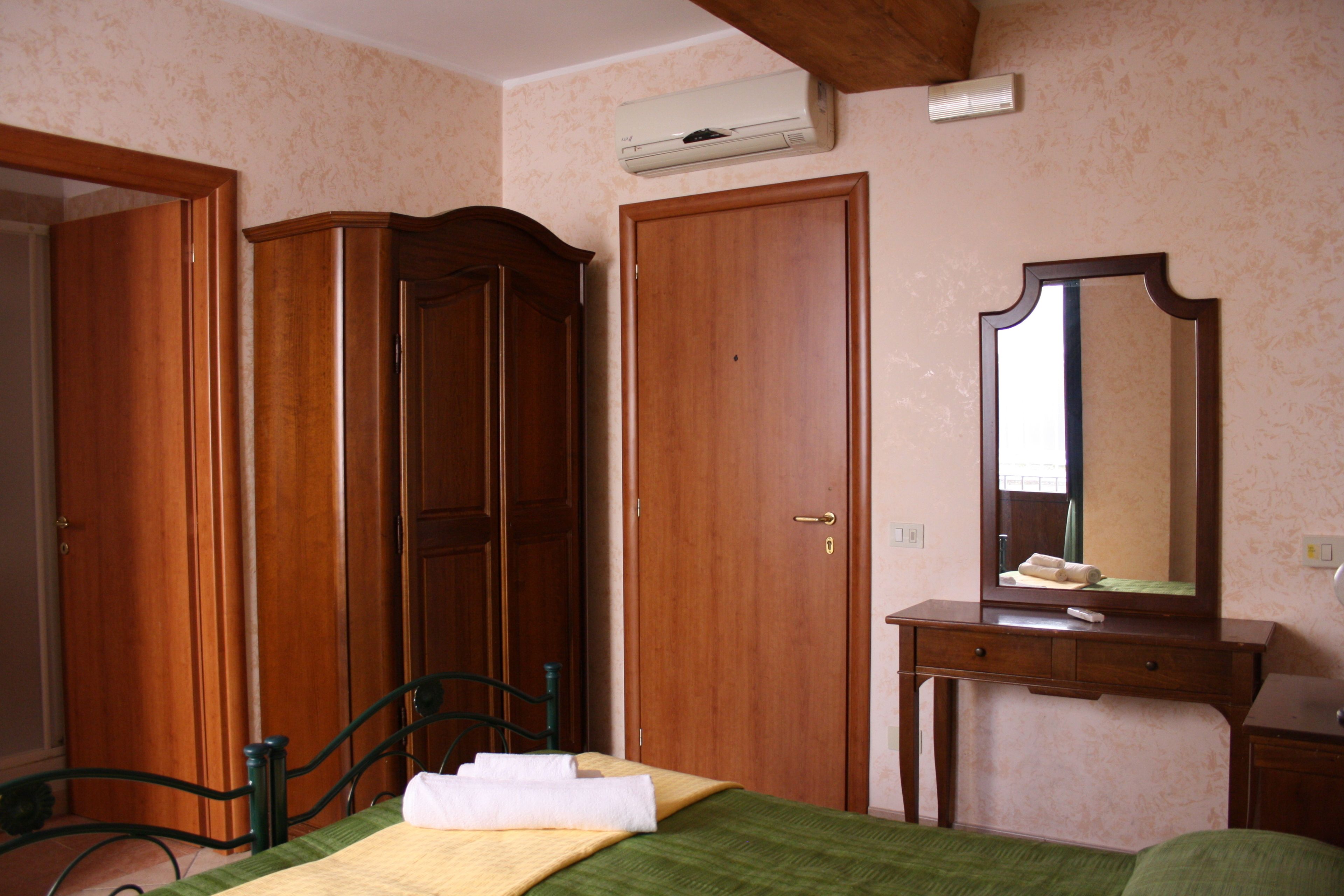 A bedroom with a bed, a dresser, a mirror, and a wardrobe.
