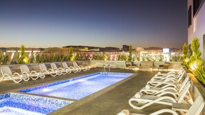 Un espace piscine aménagé sur le toit, avec des chaises longues et une piscine.