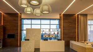 Un espace d’accueil moderne avec un comptoir de réception en bois, un présentoir blanc et une sélection d’objets décoratifs.
