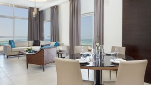 Ein modernes Hotelzimmer mit Essbereich, einer Sitzecke und Meerblick.