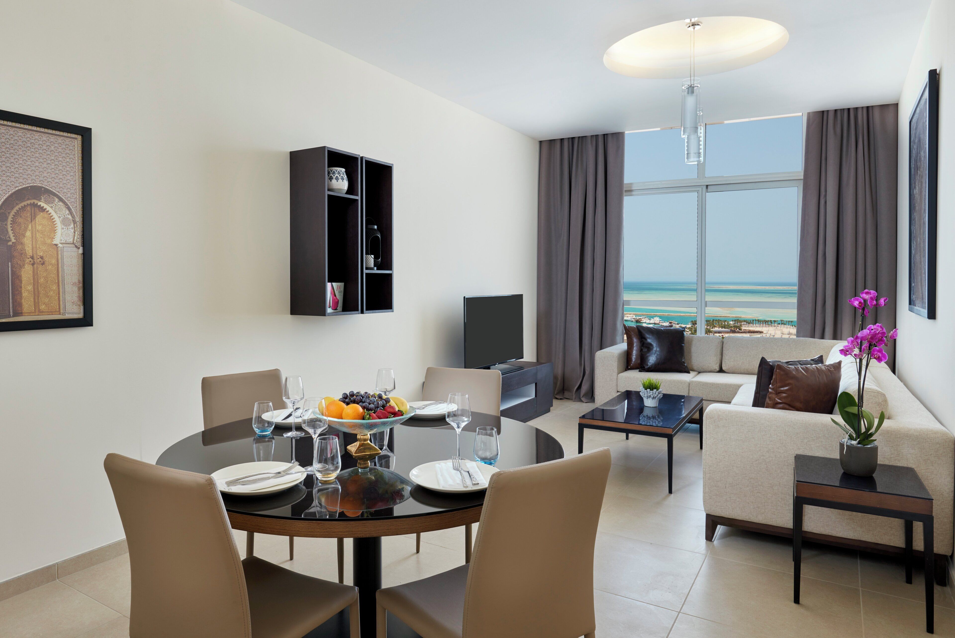 Una sala de estar moderna con comedor, un sofá, una mesita de centro y vista a la playa.