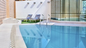 A modern pool area with clear blue water, metal pool ladders, and two lounge chairs with blue cushions. - Staybridge Suites Doha Lusail by IHG (Doha)