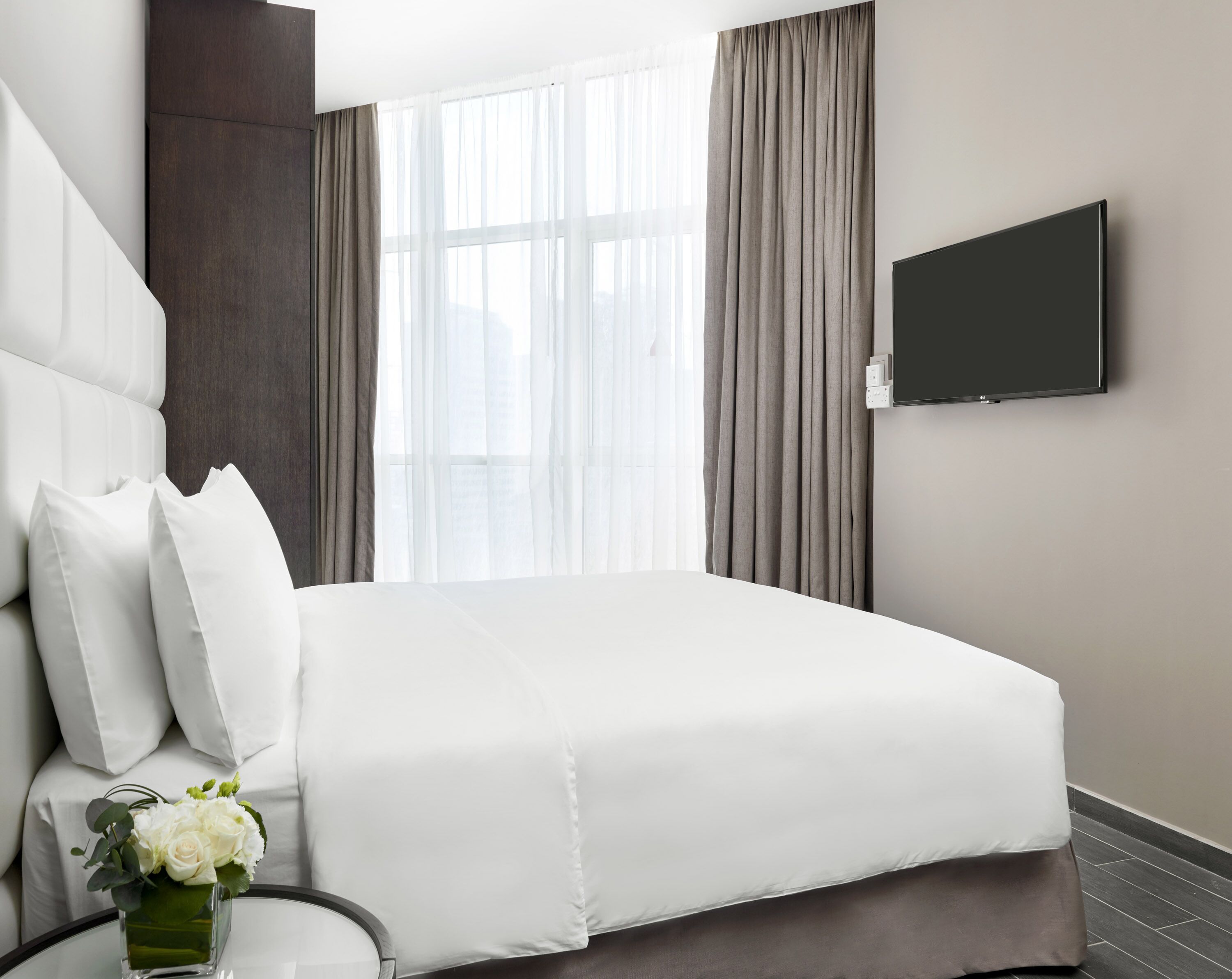 Hotelkamer met een groot bed, een wandtelevisie en een raam met gordijnen.