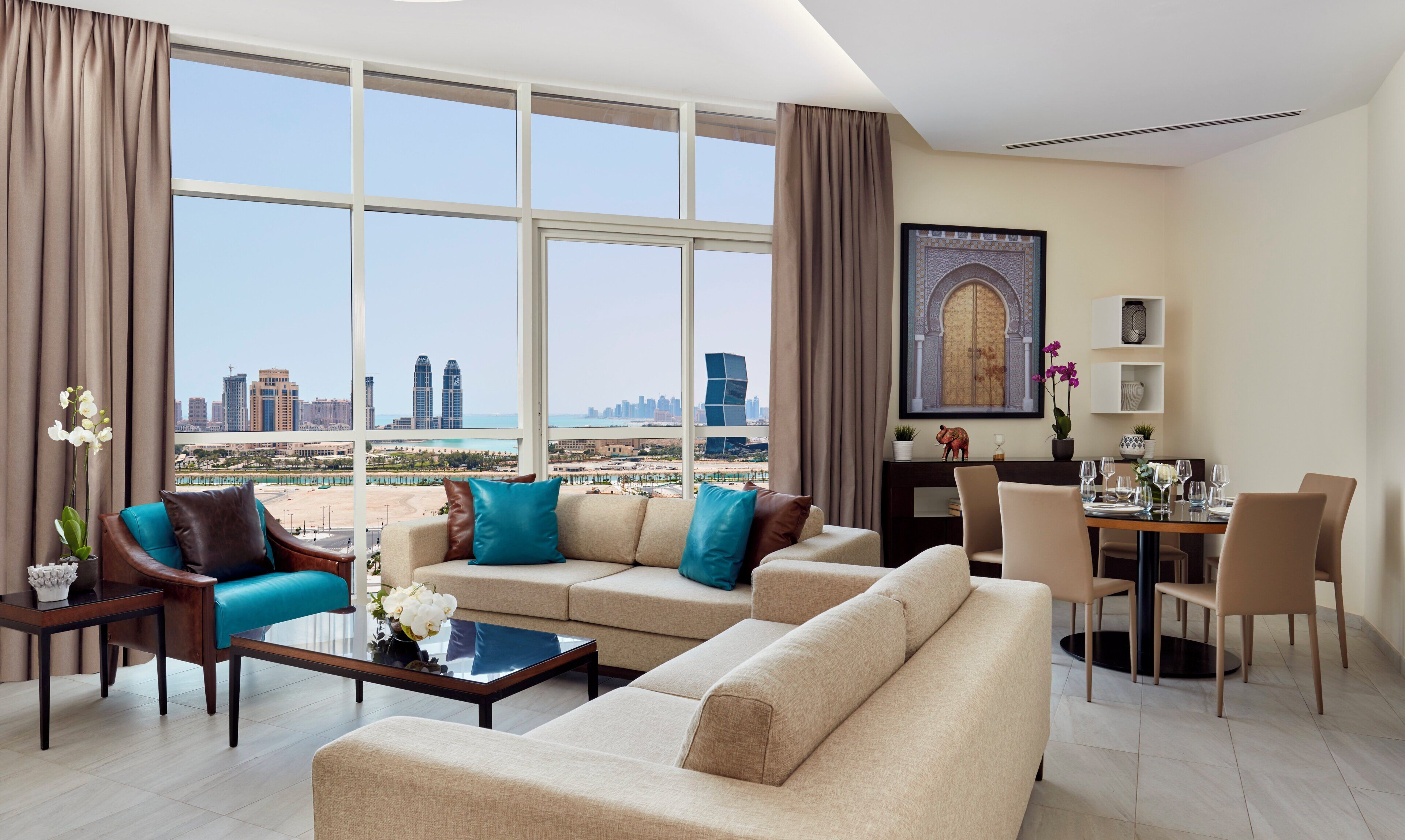 Una sala moderna con sofá, sillones, una mesa de centro y un comedor con vistas al horizonte de la ciudad.