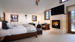 Une chambre à coucher avec un lit, une cheminée, un téléviseur et une fenêtre.