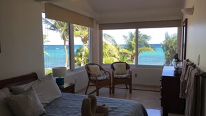 Ein Schlafzimmer mit einem Bett, zwei Stühlen, einer Kommode und Meerblick.