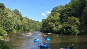 A river with people floating on blue rafts surrounded by lush greenery.