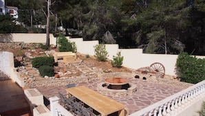 A patio with a stone fire pit, a wooden table, and a seating area.