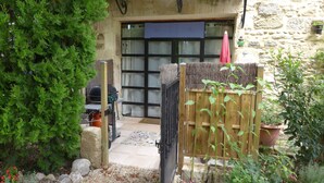 A stone building with a wooden gate, a barbecue grill, and potted plants. - "Le Kiwi" - sleeps 2 self catering studio gite 10mins from Avignon! (Rognonas)