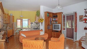 A kitchen and living room with wooden cabinets, a sofa, and a television. - Calice Al Cornoviglio: Cà de Mino (Calice al Cornoviglio)