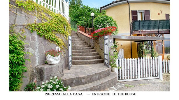 A stone staircase leading to a house entrance with a white picket fence, a balcony with a black railing, and a lamp post. - Calice Al Cornoviglio: Cà de Mino (Calice al Cornoviglio)